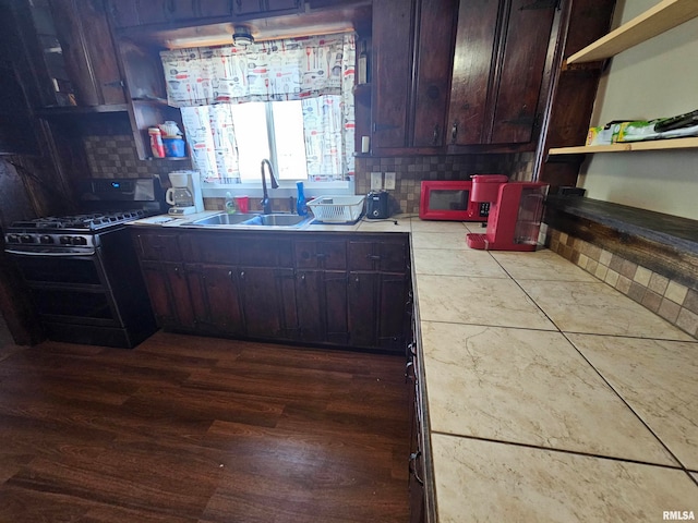 kitchen featuring tasteful backsplash, sink, dark brown cabinets, hardwood / wood-style flooring, and black appliances