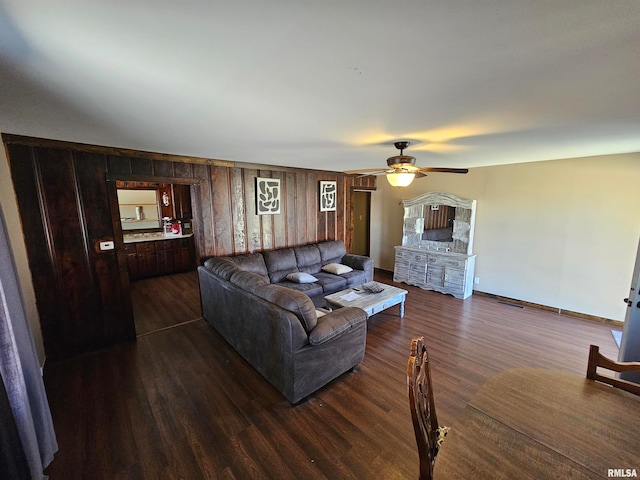 living room with wooden walls, ceiling fan, and dark hardwood / wood-style floors