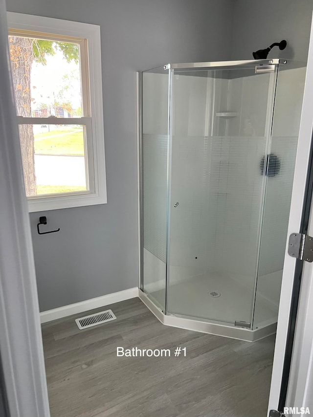 bathroom with a shower with shower door and wood-type flooring