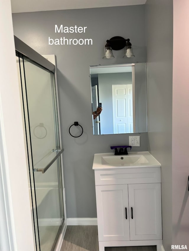 bathroom with hardwood / wood-style floors, vanity, and an enclosed shower