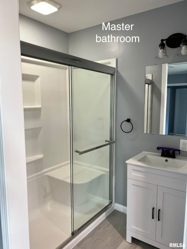 bathroom featuring vanity, a shower with shower door, and wood-type flooring