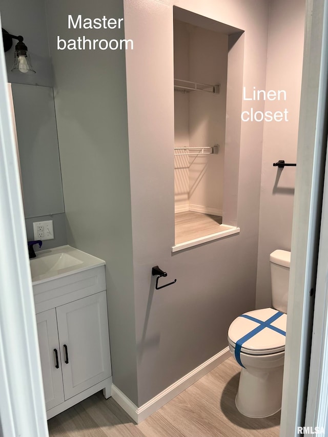 bathroom featuring toilet, vanity, and hardwood / wood-style flooring