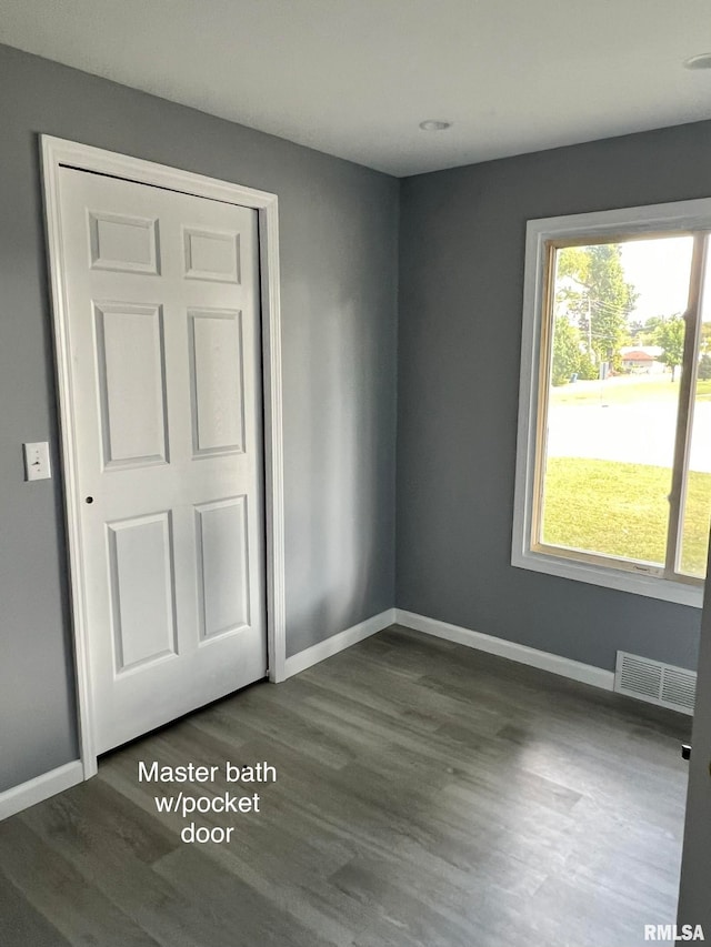 unfurnished room featuring a healthy amount of sunlight and dark hardwood / wood-style flooring