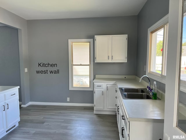 kitchen with white cabinets, light hardwood / wood-style flooring, and sink