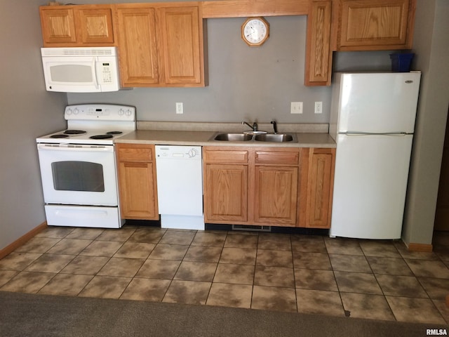 kitchen featuring white appliances, dark tile flooring, and sink