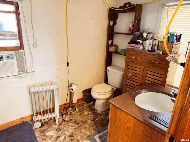 bathroom with baseboards, toilet, radiator, vanity, and cooling unit
