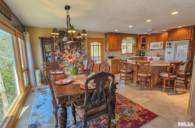 tiled dining room with plenty of natural light and ceiling fan with notable chandelier