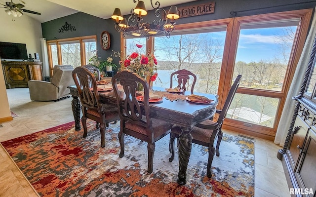 tiled dining room featuring lofted ceiling, ceiling fan with notable chandelier, and a healthy amount of sunlight