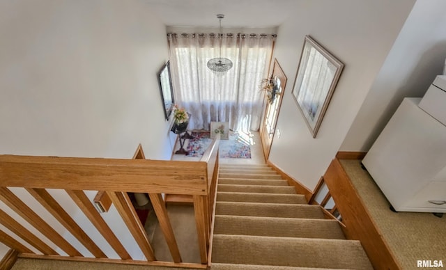 stairs with an inviting chandelier, plenty of natural light, a towering ceiling, and light carpet