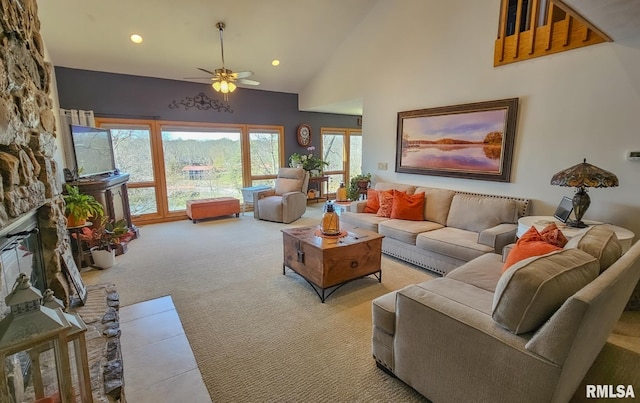 carpeted living room featuring high vaulted ceiling, ceiling fan, and a stone fireplace