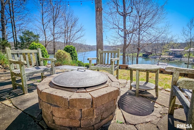 view of terrace with an outdoor fire pit and a water view