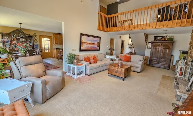 living room with a notable chandelier, light carpet, and a high ceiling