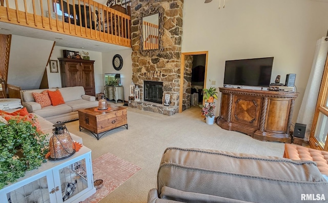 carpeted living room with a stone fireplace and a high ceiling