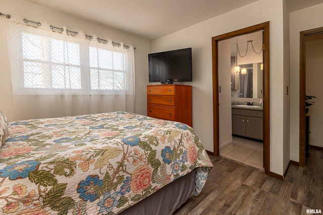 bedroom with connected bathroom, dark wood-type flooring, and sink