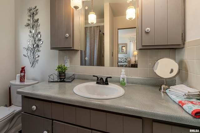 bathroom with vanity, tasteful backsplash, and toilet