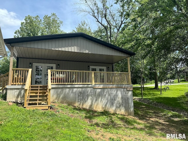 rear view of property with covered porch and a yard