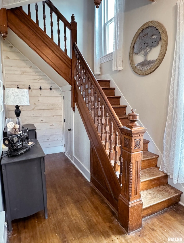 stairs featuring wooden walls and hardwood / wood-style floors