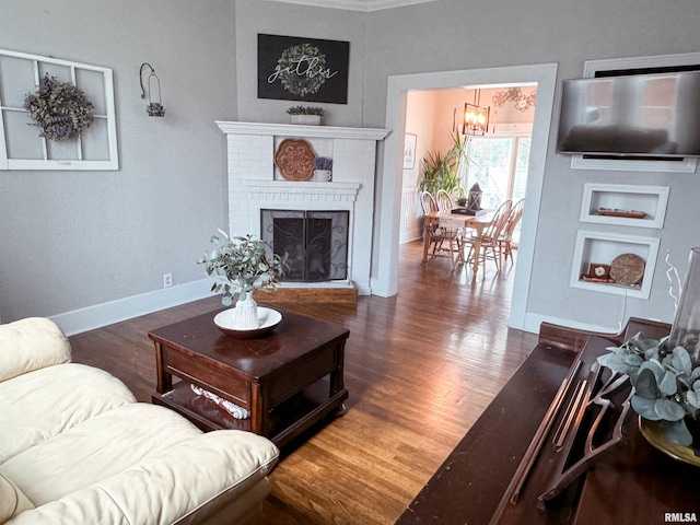 living room with dark wood-type flooring, a fireplace, and a chandelier