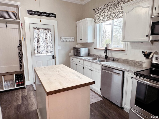 kitchen with white cabinets, sink, a kitchen island, dark wood-type flooring, and stainless steel appliances