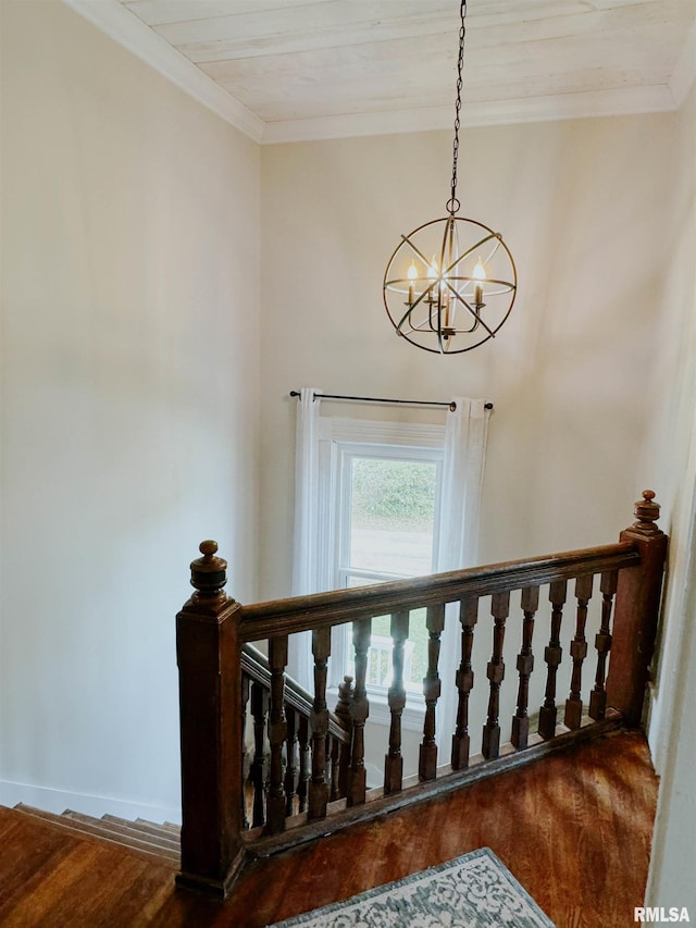 staircase with a notable chandelier, hardwood / wood-style flooring, and ornamental molding