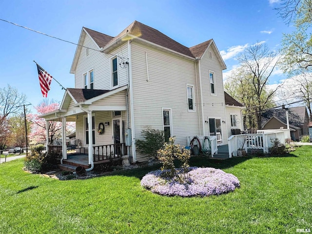 rear view of house featuring a lawn and covered porch