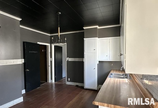 kitchen with ornamental molding, sink, dark wood-type flooring, and white cabinets