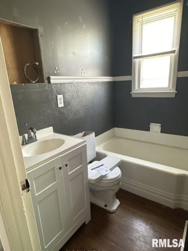 bathroom with vanity, hardwood / wood-style floors, toilet, and a washtub