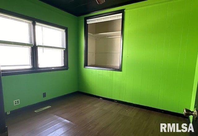 empty room featuring wood walls and dark hardwood / wood-style floors