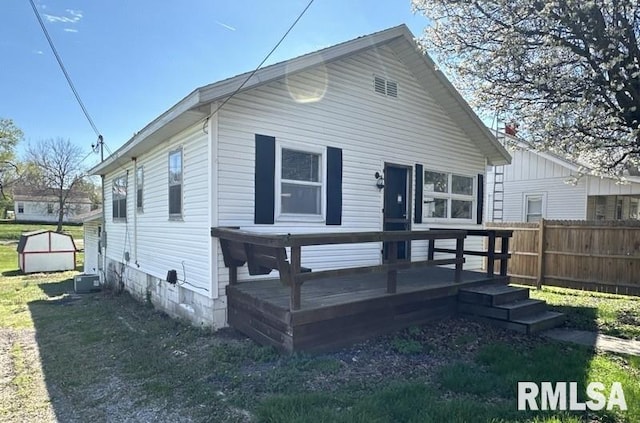 rear view of property featuring a wooden deck and a lawn