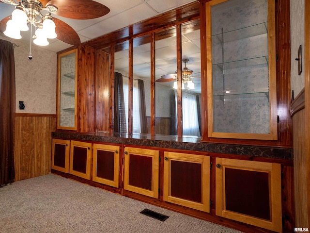 carpeted empty room with ceiling fan and wood walls