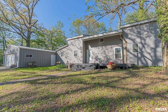 back of property featuring a garage, a lawn, and an outdoor structure