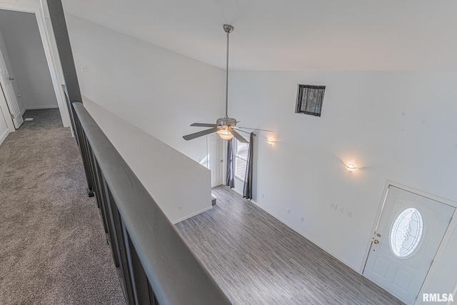 stairs featuring lofted ceiling, dark colored carpet, and ceiling fan