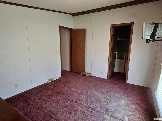 unfurnished bedroom with a wall unit AC, crown molding, and carpet flooring