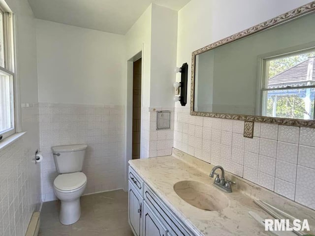 bathroom with tile floors, tile walls, toilet, and vanity with extensive cabinet space