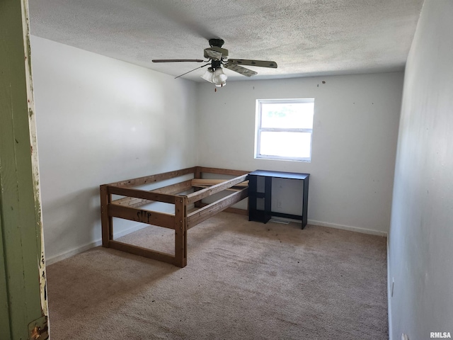 unfurnished bedroom featuring ceiling fan, a textured ceiling, and carpet flooring