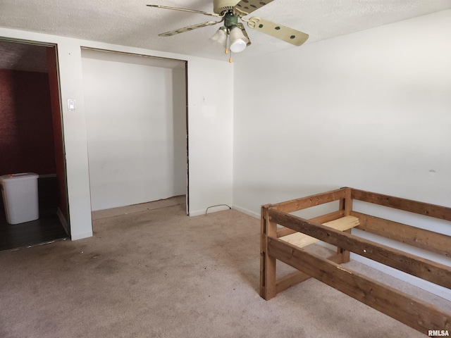 interior space with ceiling fan, a textured ceiling, and light colored carpet