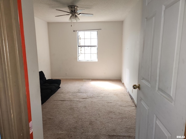 carpeted spare room featuring ceiling fan and a textured ceiling