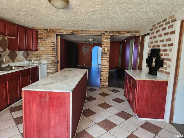 kitchen with a kitchen island, light tile patterned floors, sink, and a wood stove