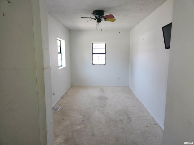 empty room featuring ceiling fan, a textured ceiling, and light carpet