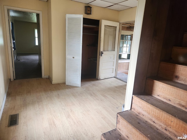 interior space featuring light hardwood / wood-style floors, a drop ceiling, and a healthy amount of sunlight