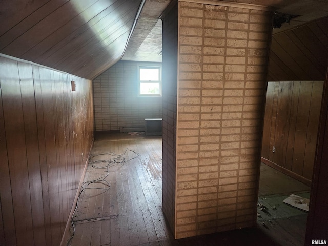 bonus room featuring wooden walls, brick wall, lofted ceiling, and hardwood / wood-style flooring