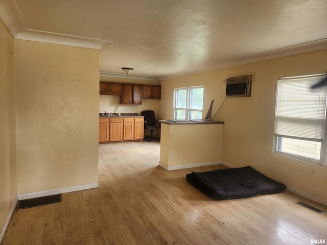 kitchen featuring sink, a wall mounted AC, crown molding, built in desk, and light wood-type flooring