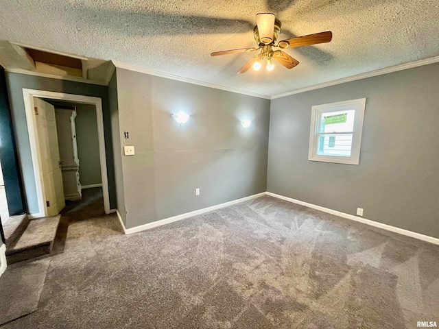 empty room with a textured ceiling, ceiling fan, carpet floors, and crown molding