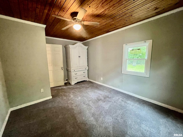 unfurnished bedroom with dark colored carpet, wood ceiling, crown molding, and ceiling fan