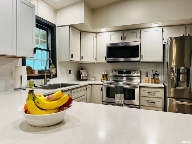 kitchen with white cabinetry, stainless steel appliances, tasteful backsplash, and sink