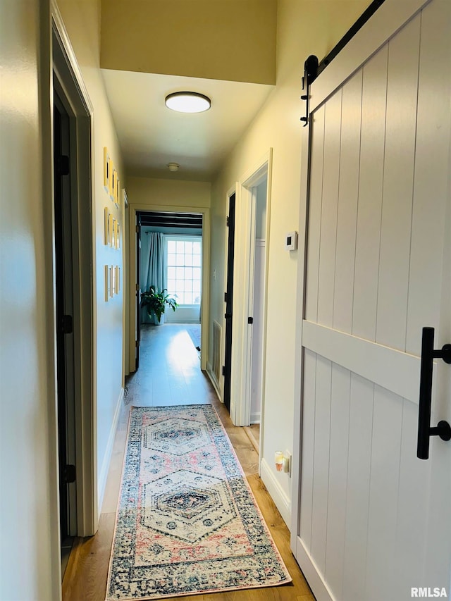 hallway featuring a barn door and light hardwood / wood-style floors