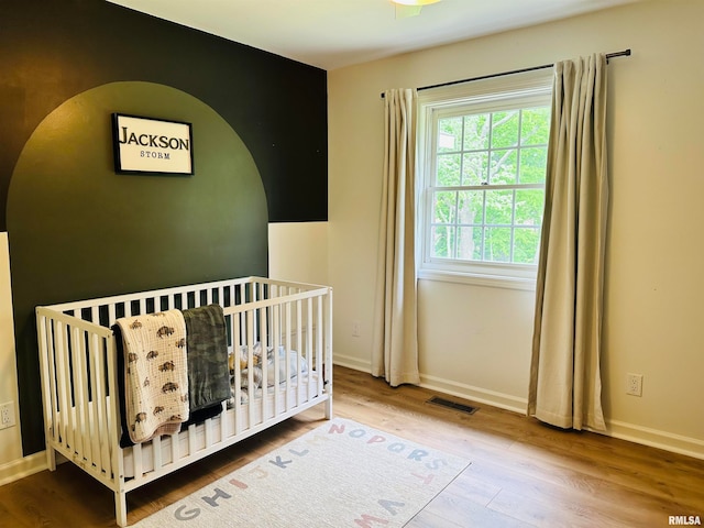 unfurnished bedroom with hardwood / wood-style floors and a nursery area