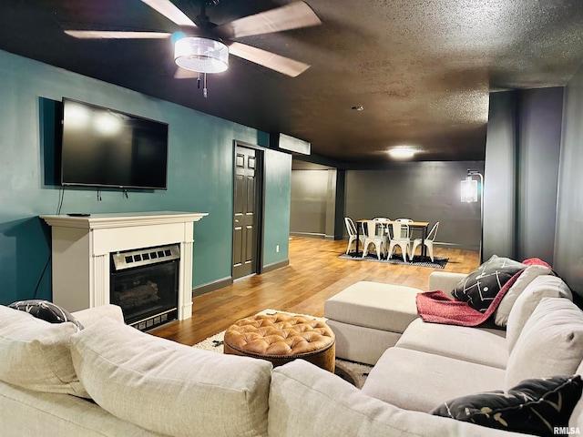 living room featuring ceiling fan, hardwood / wood-style flooring, and a textured ceiling