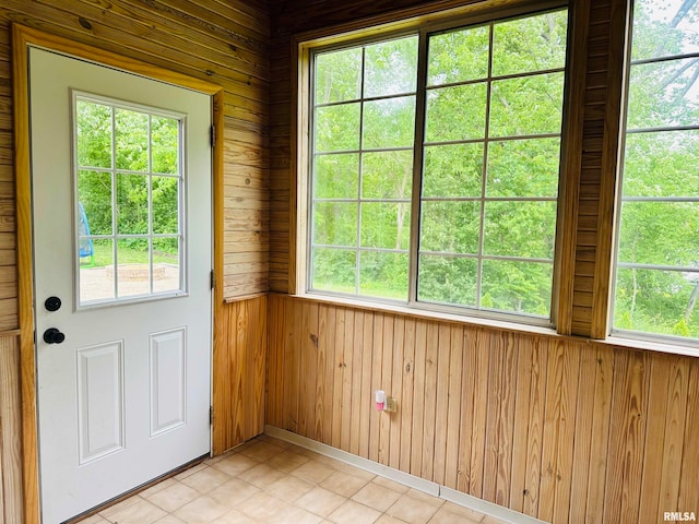 doorway featuring plenty of natural light, wood walls, and light tile floors