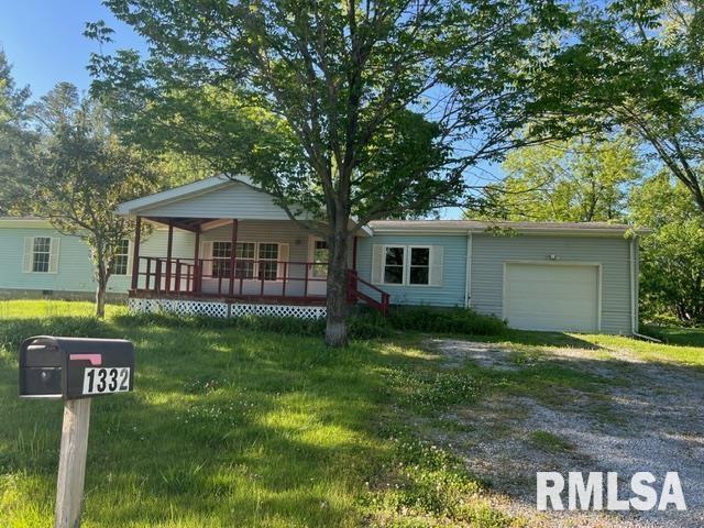 single story home with a garage, covered porch, and a front yard